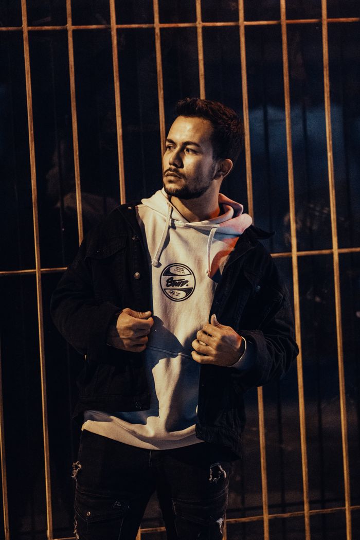 The Art of Drawing Readers In: Your attractive post title goes here Stylish man in a hoodie and jacket posing outdoors at night against a fence.