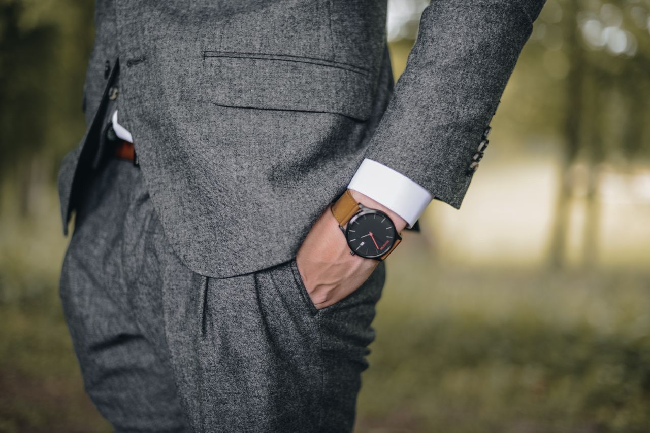 Services Close-up of a man in a tailored suit wearing an elegant wristwatch outdoors, exuding fashion and sophistication.